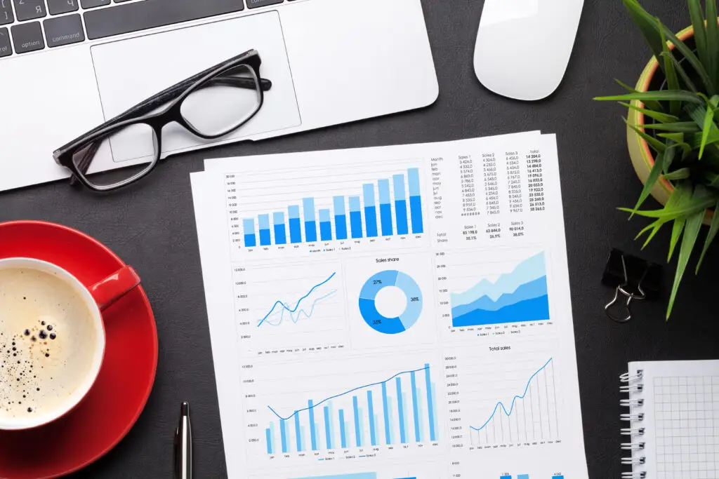 Office workplace table with report page, coffee cup, supplies and computer Flat lay. Top view
