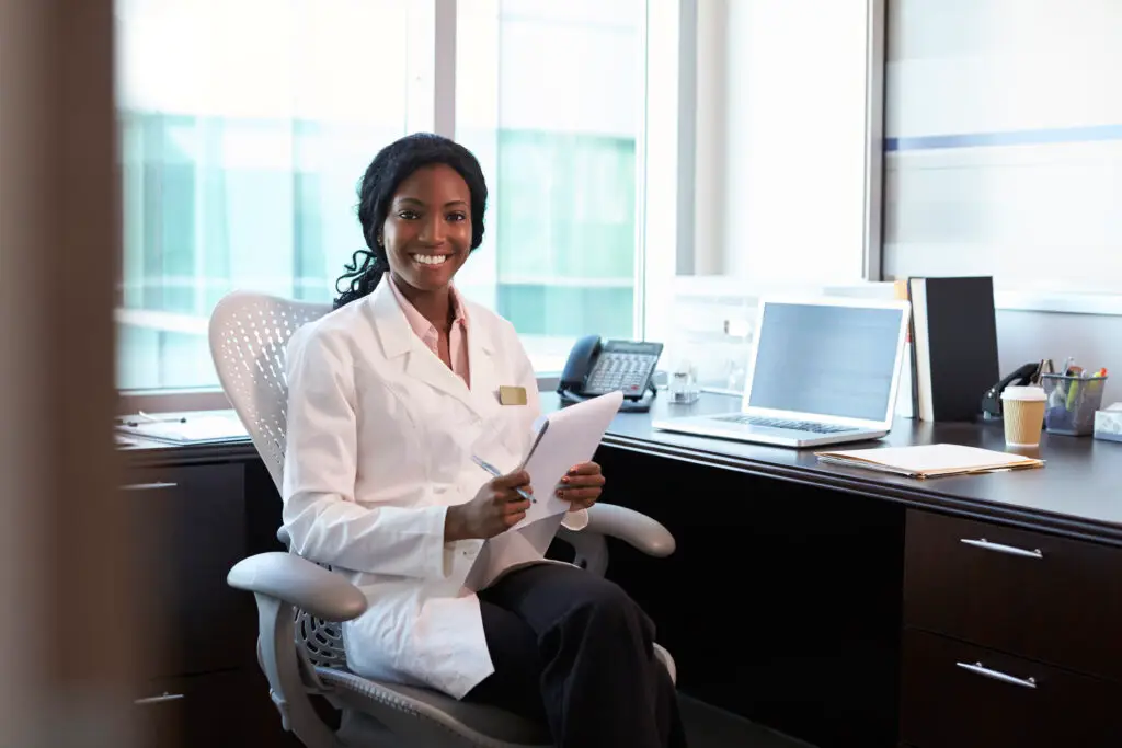 Cheerful doctor using laptop in office