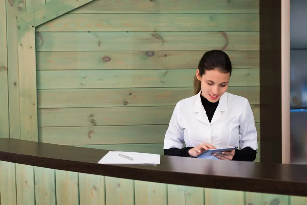 Woman in a spa recpetion uses tablet pc texting to client. Beauty and technology concept.